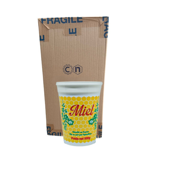 Gobelet blanc avec motif miel jaune et jaune à hexagones, devant boîte en carton.